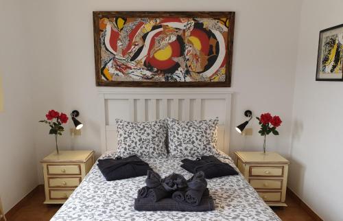 a bedroom with a bed with two night stands and a painting at Absolute Beachfront Apartment in Famara