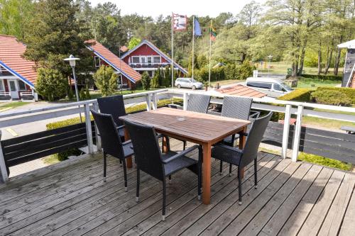 a wooden table and chairs on a deck at Vila Baldininkas in Neringa