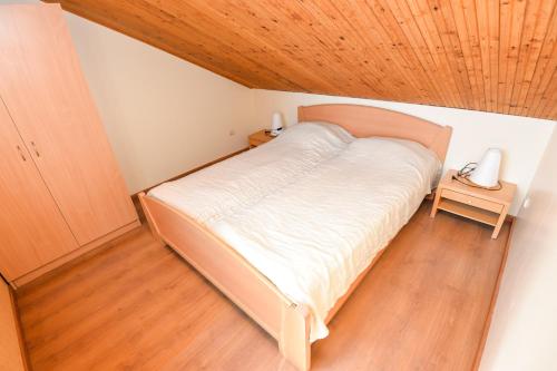 a bedroom with a large bed with a wooden ceiling at Vila Baldininkas in Neringa