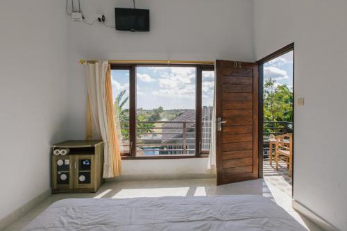 a bedroom with a bed and a large window at Pluto House in Canggu
