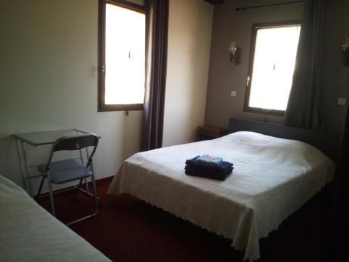 a room with a bed and a chair and two windows at Mas du Colombier in Saint-André-les-Alpes