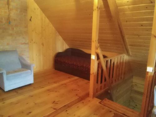 an attic room with a bed and a chair at Alisa kviečia. in Juodalaukiai