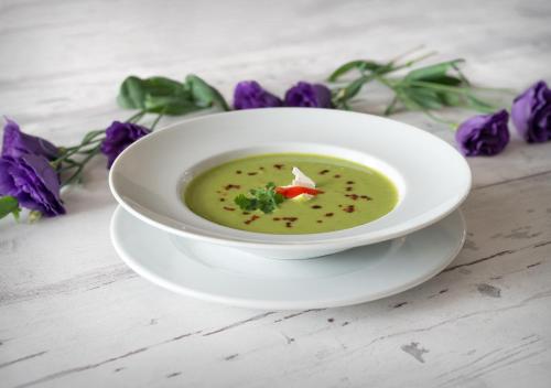a bowl of soup on a table with purple flowers at Hotel Capitol in Biała Podlaska