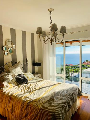 a bedroom with a bed with a view of the ocean at VILLA FELICIDADE in Arco da Calheta