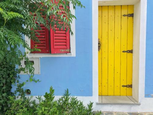 a blue building with a yellow and red window at Casa Rico Frade Garden in São Pedro do Corval