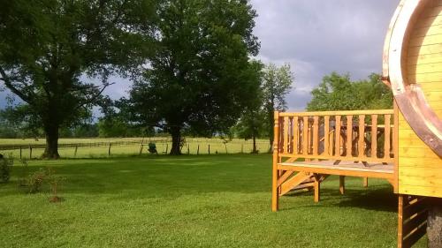 a wooden bench sitting in the grass in a field at A la RONZIERE - Le Tonneau in Pouilly-sous-Charlieu
