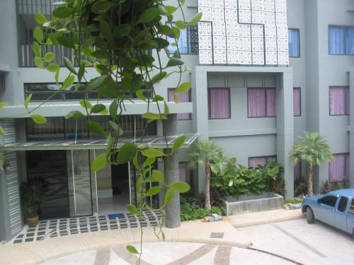 a building with a tree in front of it at Dinar Lodge in Bang Tao Beach