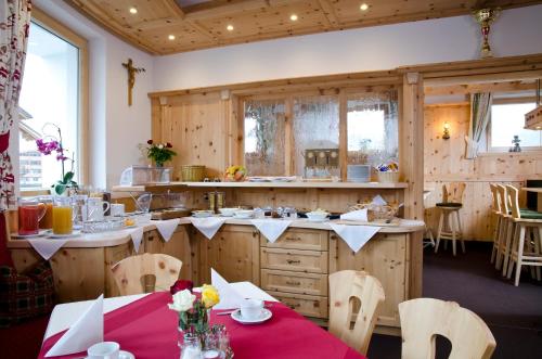 a kitchen with wooden cabinets and tables and chairs at Berghotel Rasis in Galtür