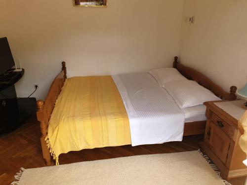 a bedroom with a bed with a yellow and white blanket at Zoro Apartments in Sveti Stefan