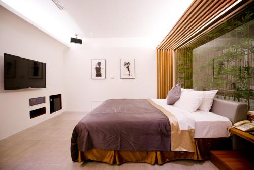 a bedroom with a large bed and a tv at Hotel Shumei Chiayi in Zhongpu