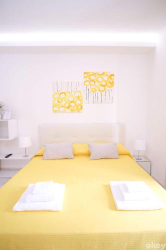 a large yellow bed with two white towels on it at Charme & Chic Studios - Bari Centro in Bari