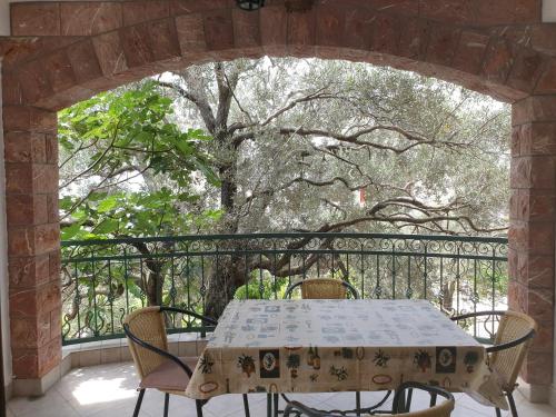 a table and chairs on a balcony with a tree at Zoro Apartments in Sveti Stefan