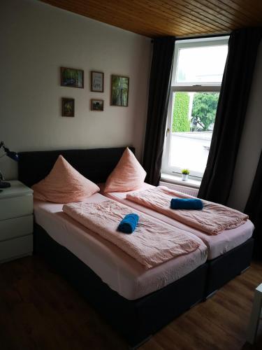 a bed with two blue pillows and a window at Rickmersstraße 61 Bremerhaven in Bremerhaven