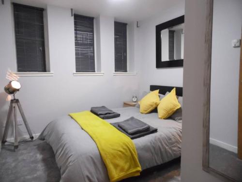 um quarto com uma cama com um cobertor amarelo em Art Deco Building on Vibrant Sauchiehall Street em Glasgow