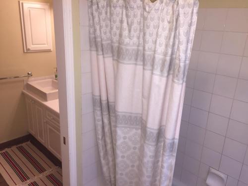 a bathroom with a shower with a white shower curtain at Brother Li Homestay in Calgary
