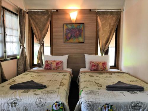 two beds in a room with windows at Seashell Coconut Village Koh Tao in Ko Tao