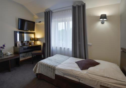 a bedroom with a bed and a desk and a window at Hotel Capitol in Biała Podlaska