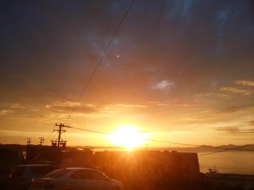 a sunset with a car parked in front of the water at Minshuku Osaki in Nishio