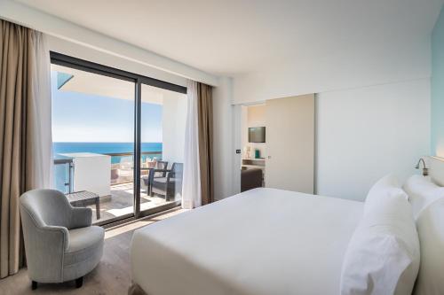 a hotel room with a bed and a chair and a window at Occidental Fuengirola in Fuengirola