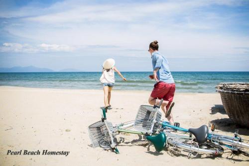 a couple of people walking on the beach at Pearl Beach Homestay - Cua Dai Beach, Hoi An in Hoi An
