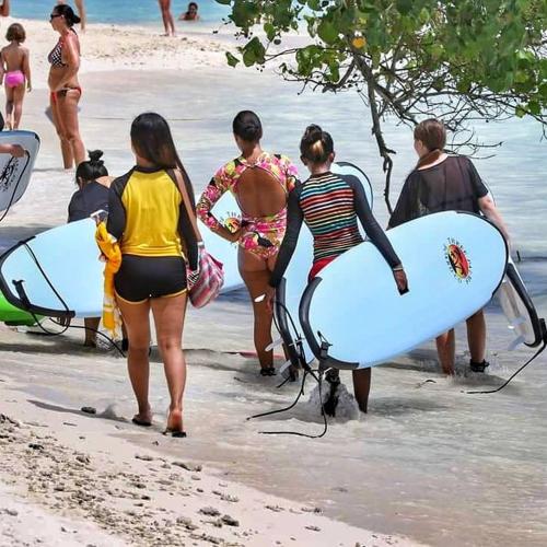 a group of people walking on the beach with surfboards at La Due Thulusdhoo in Thulusdhoo
