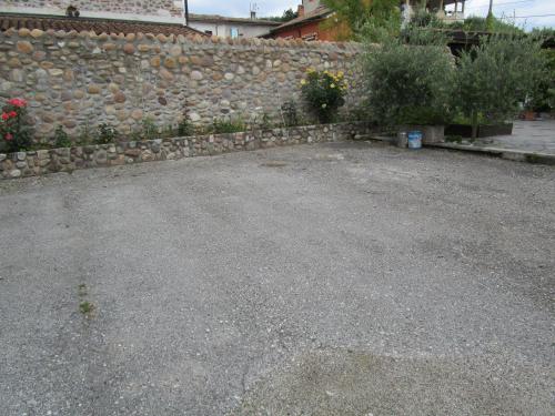 a gravel parking lot next to a stone wall at B&B Laura in Pastrengo