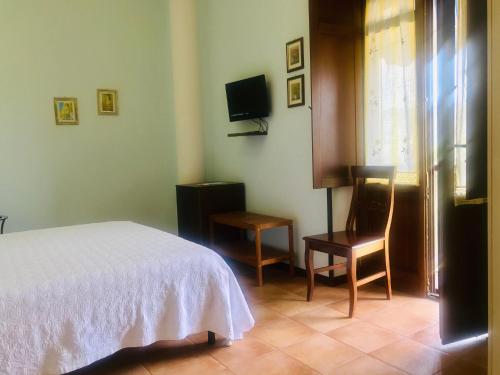 a bedroom with a bed and a chair and a television at Casa Vacanze Il Cenito in Castellabate