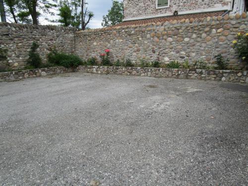 a stone wall next to a driveway next to a house at B&B Laura in Pastrengo