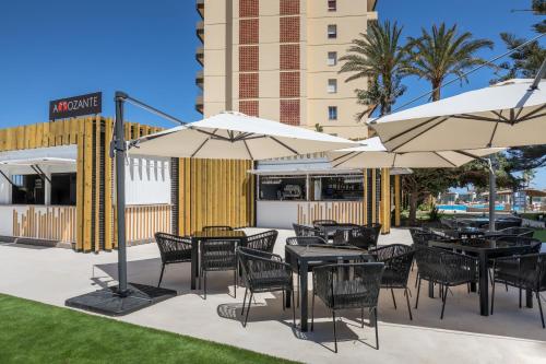 a patio with tables and chairs and umbrellas at Occidental Fuengirola in Fuengirola