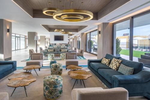 a lobby with blue couches and tables and windows at Occidental Fuengirola in Fuengirola