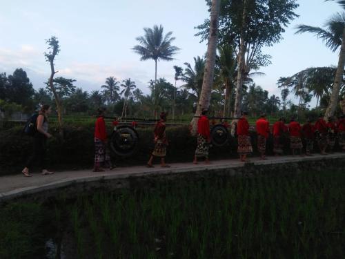 a group of people in red shirts standing on a sidewalk at Tereng Wilis Jungle Inn in Tetebatu