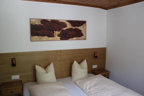 łóżko z dwoma poduszkami i obrazem na ścianie w obiekcie Apartments Alpenrose w mieście Flirsch
