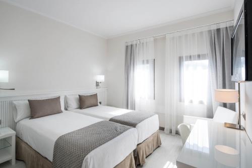 a white bedroom with a large bed and a window at Catalonia Roma in Barcelona