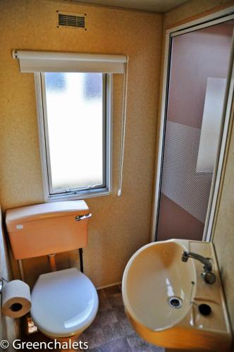 une salle de bain avec un lavabo et des toilettes et une fenêtre dans l'établissement Greenchalets Lei Suves retro, à Roquebrune-sur Argens