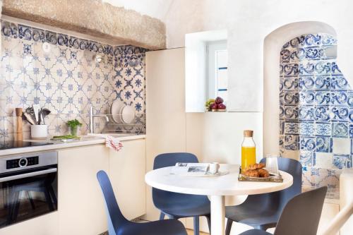 a kitchen with a white table and blue chairs at Archi-Pelago Alfama Design Suites Guesthouse in Lisbon