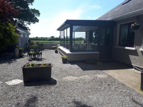 a house with a patio with plants in a yard at The Ring Farmhouse in Birr