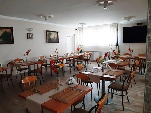 Un comedor con mesas y sillas y un gran ventanal. en Márvány Panzió, en Hajdúszoboszló