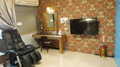 a room with a desk and a tv and a chair at Sydney Motel in Tucheng