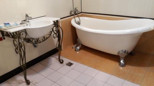 a bath tub and a sink in a bathroom at Sydney Motel in Tucheng