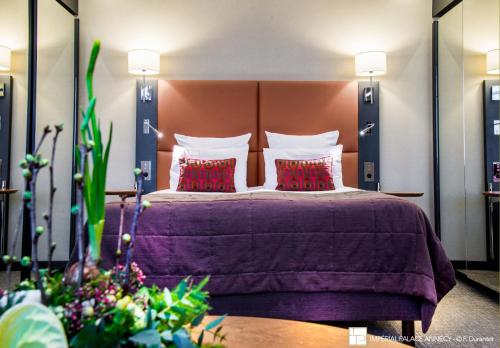 a bedroom with a large bed with red pillows at Impérial Palace in Annecy