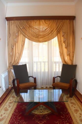 a living room with two chairs and a glass table and a window at Christy Hotel in Goris