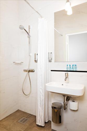 a white bathroom with a sink and a shower at Hotel Vasa, BW Signature Collection in Gothenburg