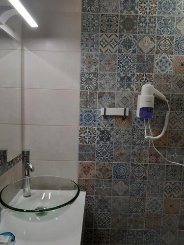 baño con lavabo de cristal y azulejos en la pared en Hotel Lozite, en Sozopol