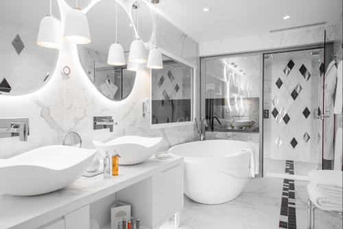 a white bathroom with two sinks and a tub at Impérial Palace in Annecy