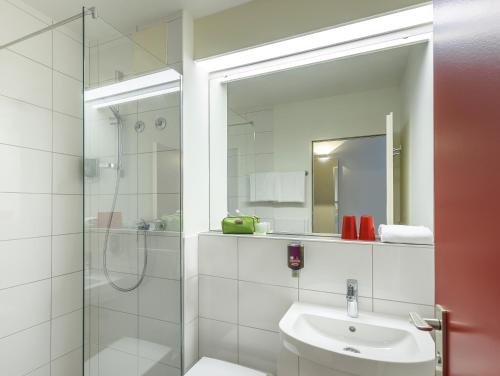 a bathroom with a glass shower and a sink at Hotel am Schlosspark Herten in Herten