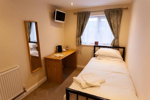 a bedroom with a bed and a desk and a window at Nelthorpe Arms in Barton upon Humber