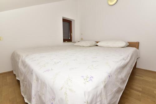 uma cama branca com duas almofadas em cima em Studio apartment The View em Malinska