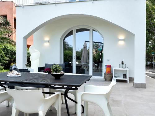 eine Terrasse mit einem schwarzen Tisch und weißen Stühlen in der Unterkunft Villa sulla spiaggia tra Catania e Siracusa in Agnone Bagni