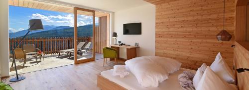 a bedroom with a bed and a balcony with a view at Tratterhof Mountain Sky Hotel in Maranza