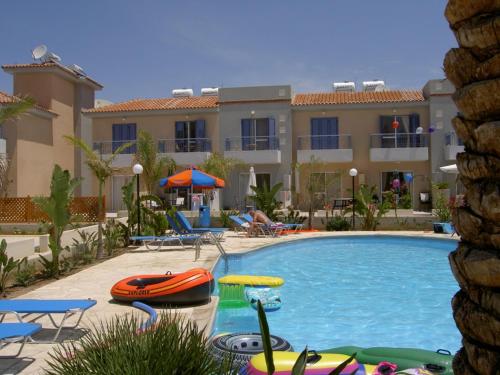 a pool at a resort with rafts and umbrellas at Helios Cottages in Paphos City